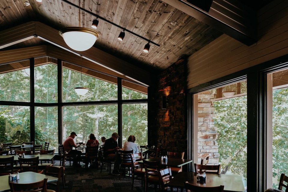 people sitting down and eating inside a restaurant with other chairs and tables around them