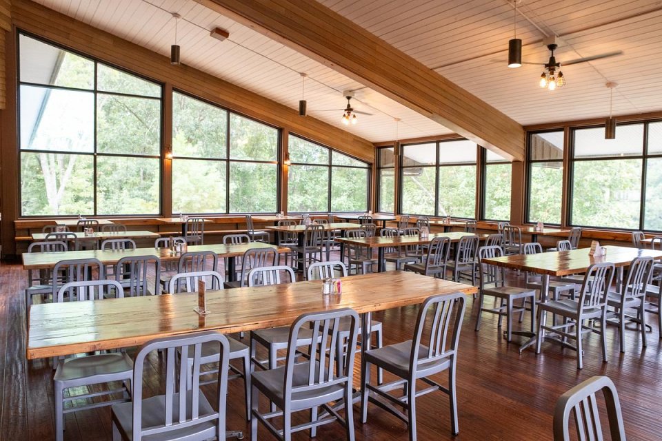 several rows of tables and chairs inside a wooden room with large windows