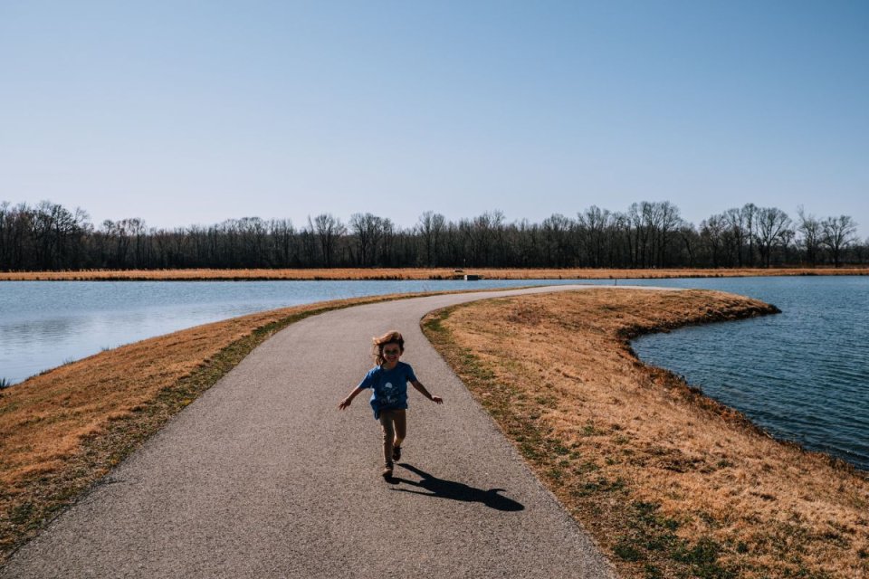 child running on concrete path away from water