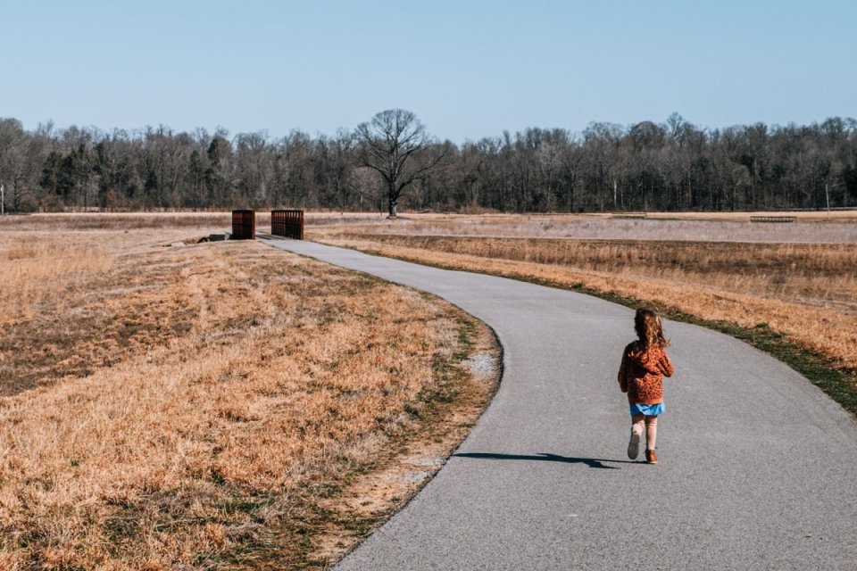 child walking on concrete path towards a bridge