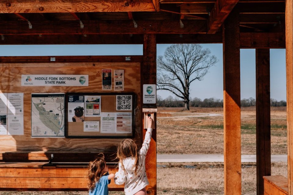 two young children playing with a wooden post board with information on it
