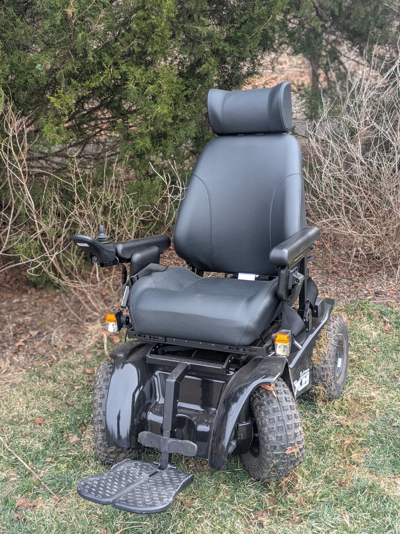 An all-terrain wheelchair sits empty upon green grass.