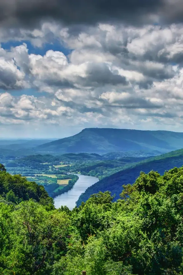 Lush green hills with a winding river under a cloudy sky.
