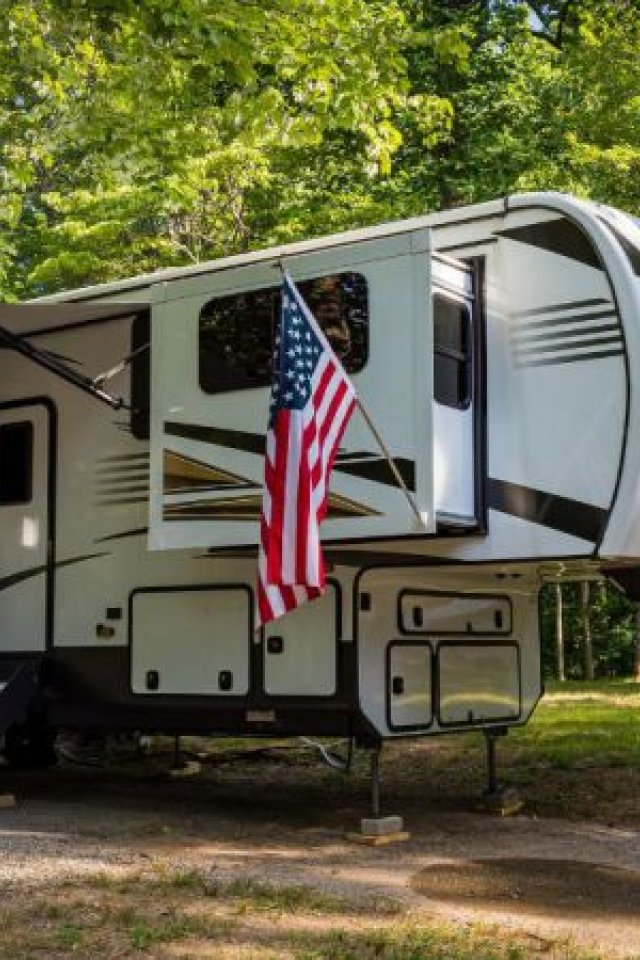 An RV parked in a forest surrounded by trees. 