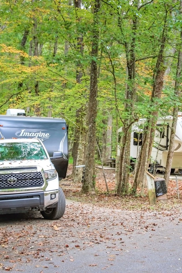 Trucks and RVs parked in a wooded camping area.