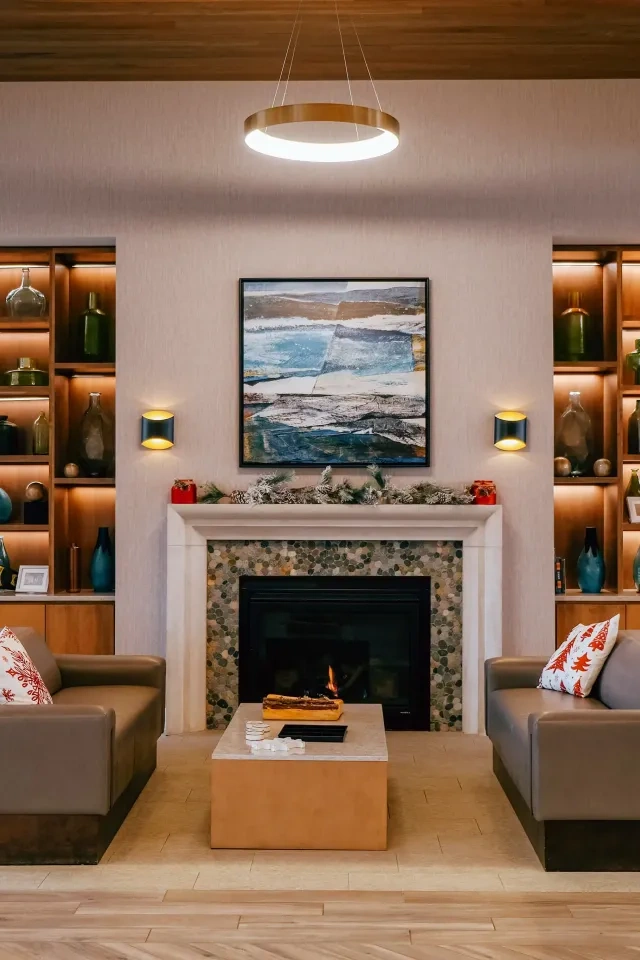 Modern living room with cozy couches, fireplace, and decorative shelves.