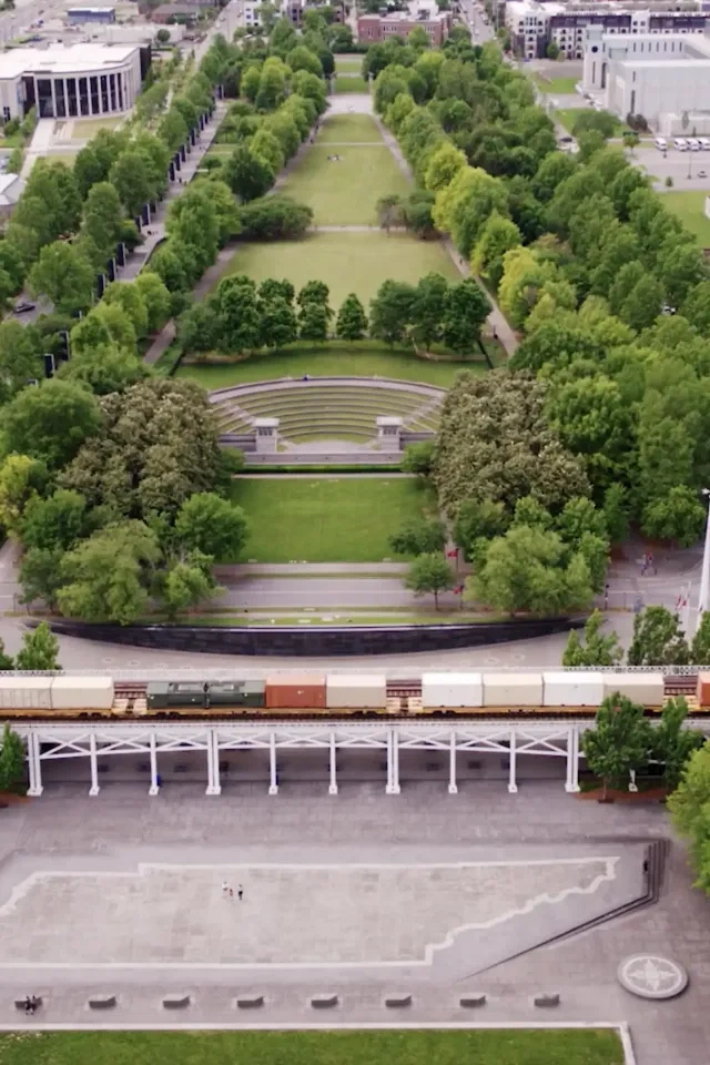 Aerial view of a city park with train tracks and surrounding buildings.