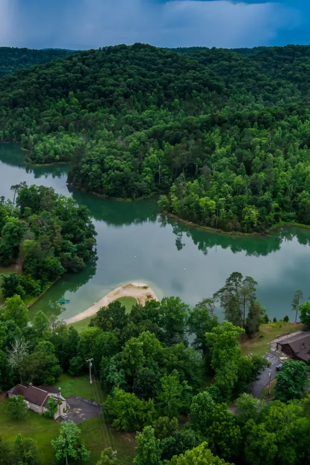 Lush green hills and river with houses nestled among trees.