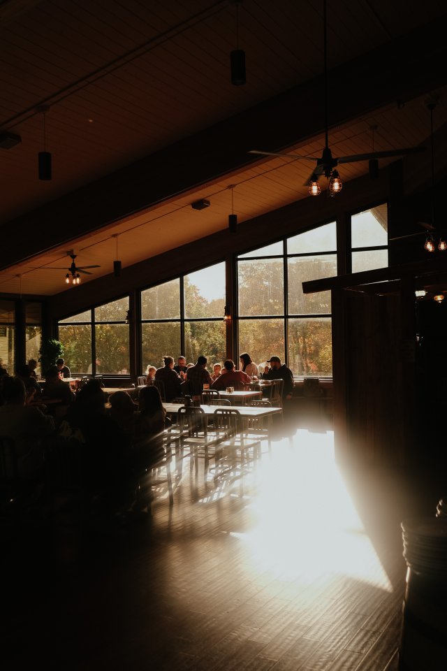 light streaming in from the back windows while families eat in the dining room of the restaurant