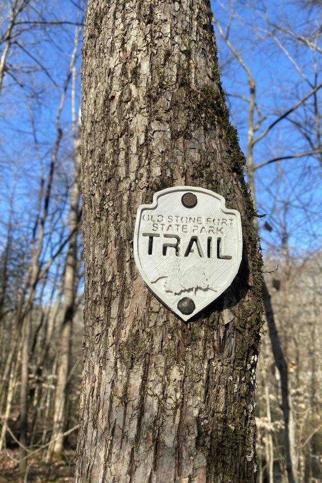 sign placed on a tree that says old stone fort state park trail
