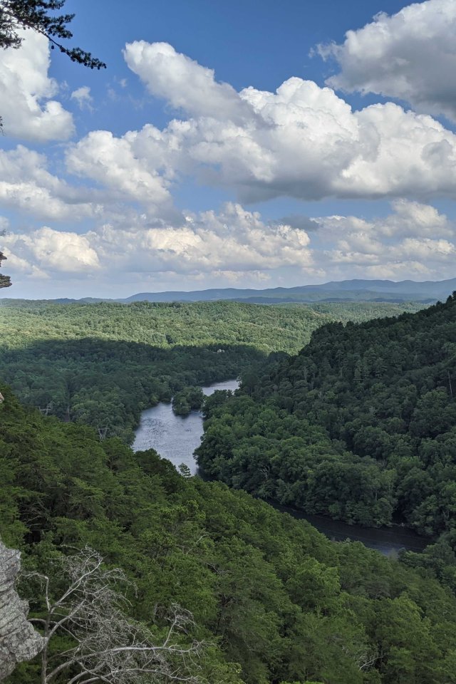 View of landscape with a river, a stone mountain on the left and trees everywhere