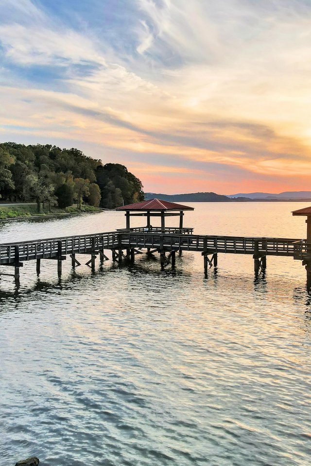 Sunset view over a lake with a wooden pier and colorful sky.