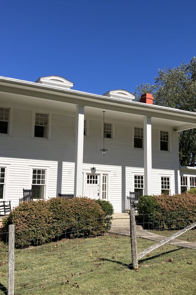 two story white house with four thin pillars in front of it for stability