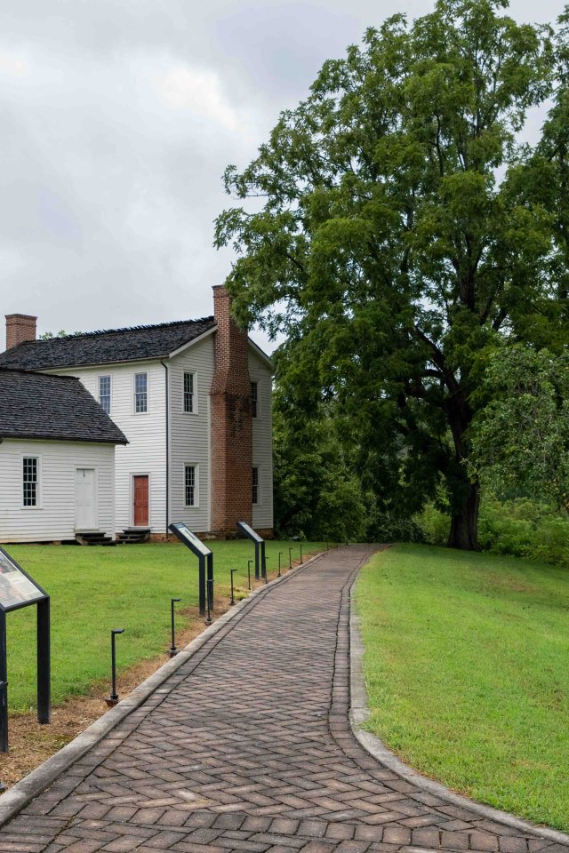 concrete trail that leads towards white house with several chimneys.