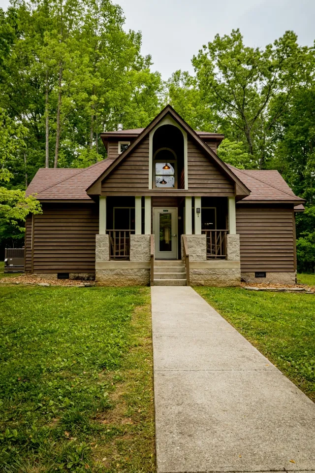 Brown wooden house with a central pathway and lush greenery.