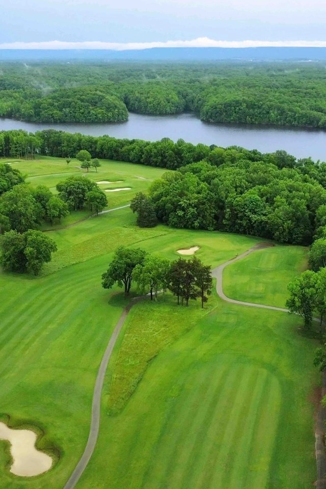 A lush green golf course on a peninsula surrounded by blue lake water