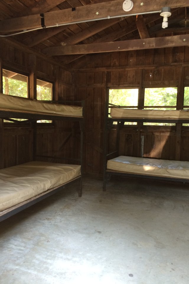 Two empty wooden bunk beds in a rustic cabin.