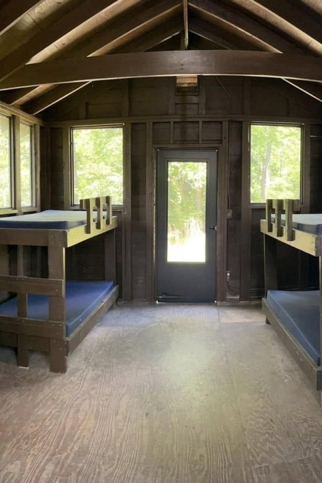 Interior of a rustic cabin with bunk beds and wooden beams.