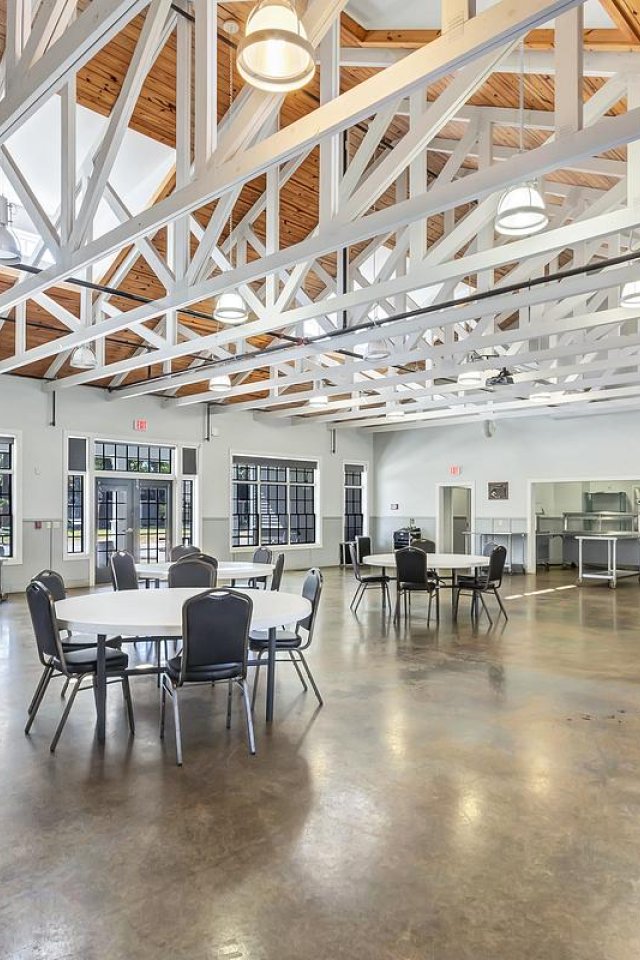 Spacious cafeteria with wooden ceiling beams and multiple seating areas.