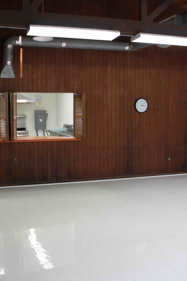 Empty room with brown wood-paneled walls, white floor, and a clock.