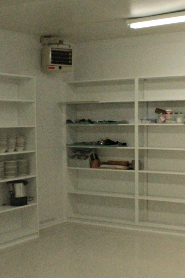 Empty white shelves in a well-lit room, with a few small items on the right.