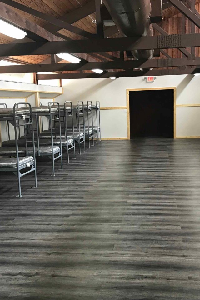 Large dorm room with rows of metal bunk beds on both sides.