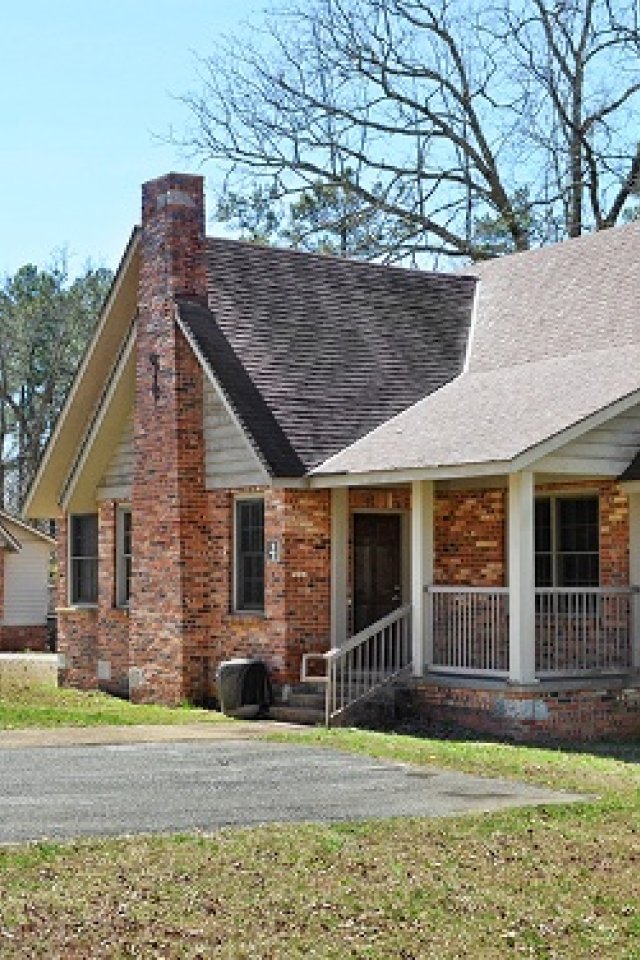 Brick houses with chimneys in a wooded area under a clear sky.