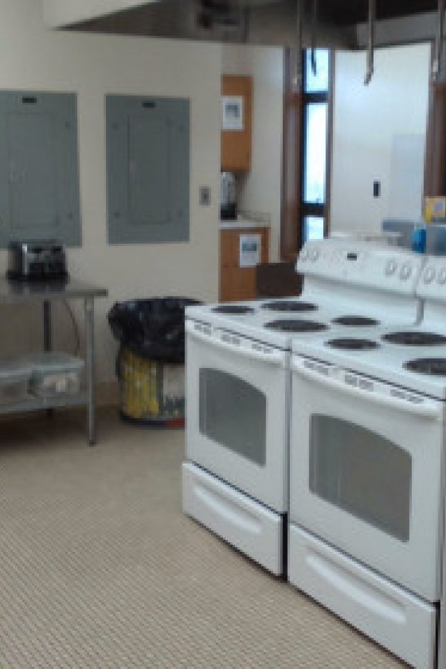 Kitchen with double stoves, microwaves, and sinks under natural light.