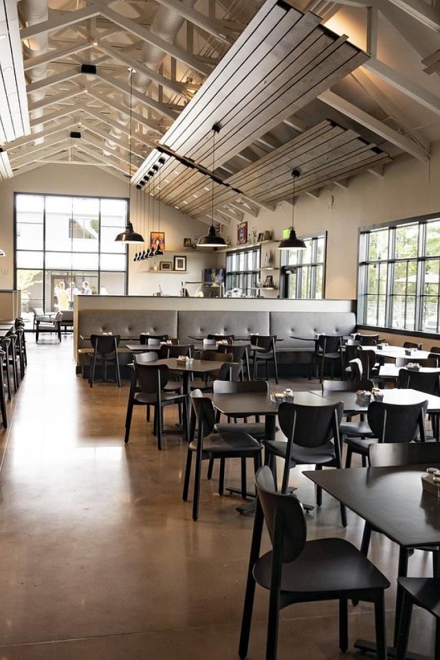 Spacious, modern restaurant interior with wooden tables and large windows.