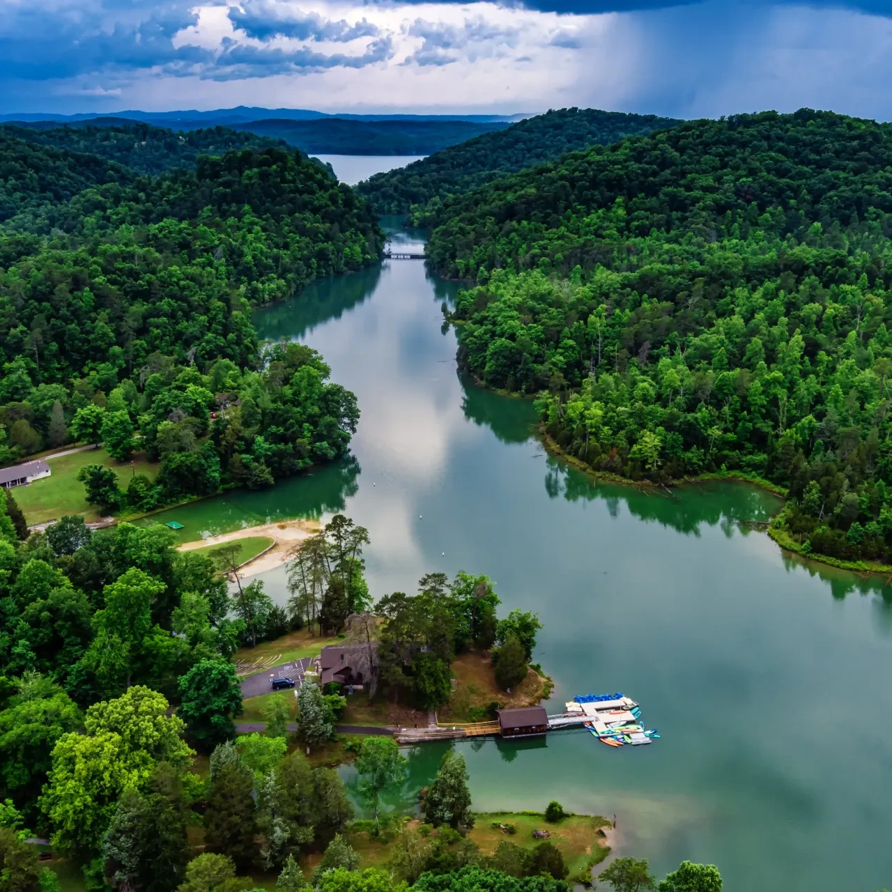 River winding through lush green hills under cloudy sky.