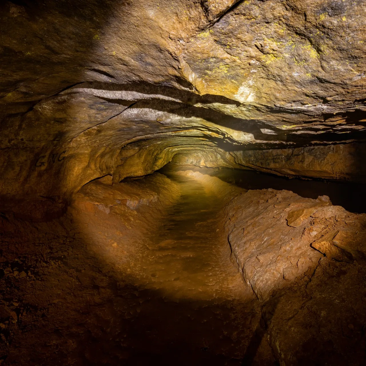 Dimly lit cave tunnel with rocky walls and a rough dirt path.