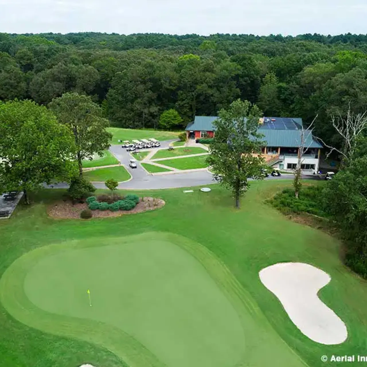 Aerial view of a golf course with clubhouse and trees.