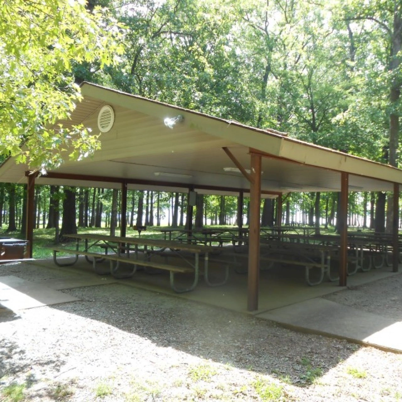 Covered picnic area with tables in a wooded park.