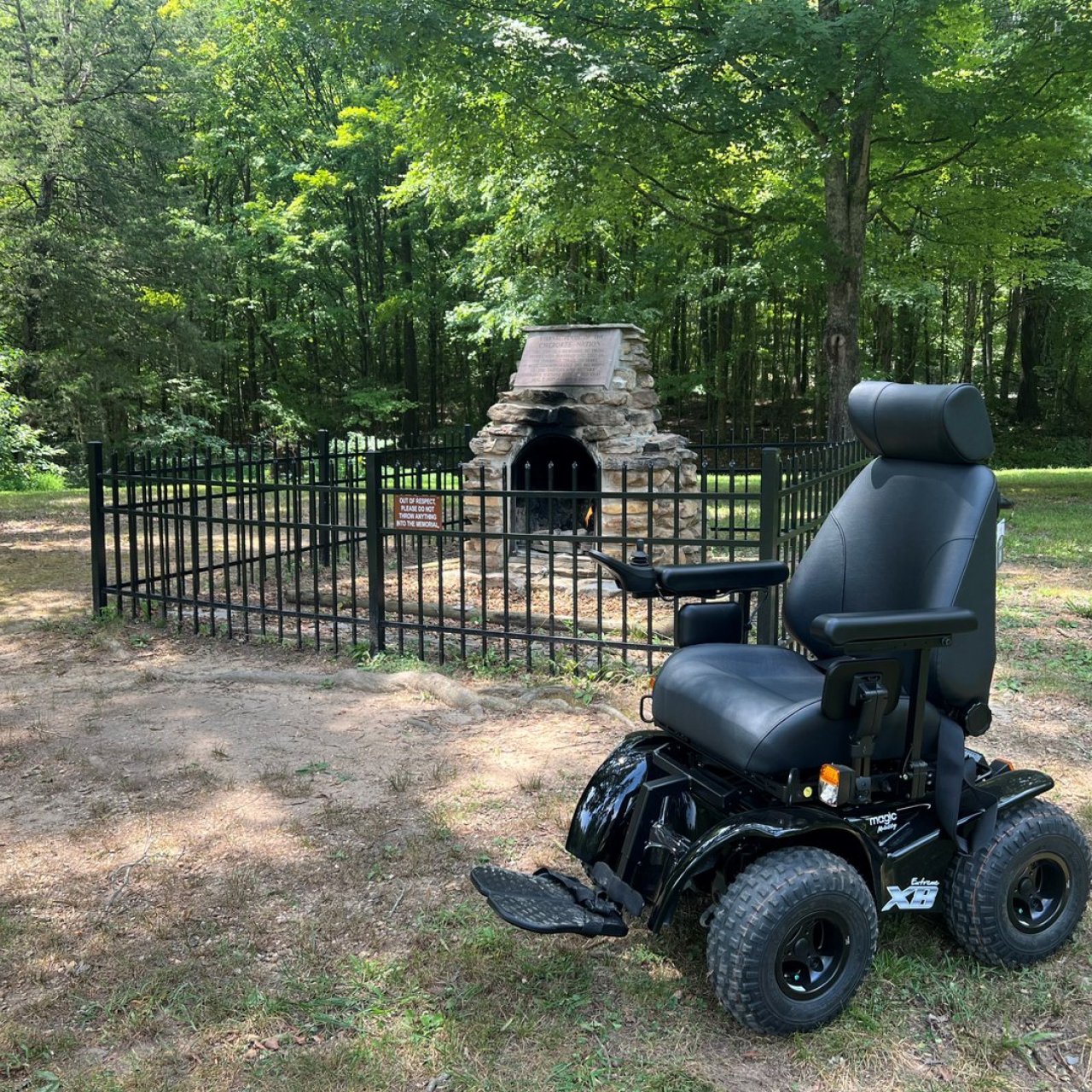 Wheelchair in front of historic landmark that is fenced in on flat terrain