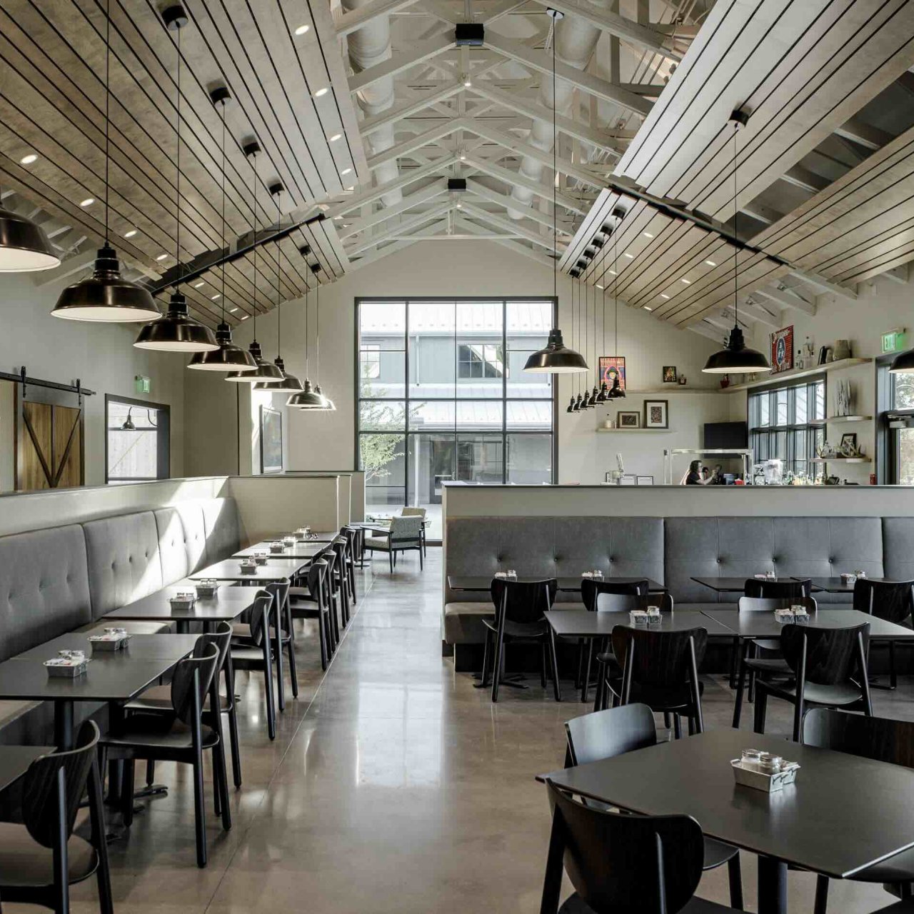 inside restaurant with booths, dining tables, chairs, overhead lighting, large windows, and a bar