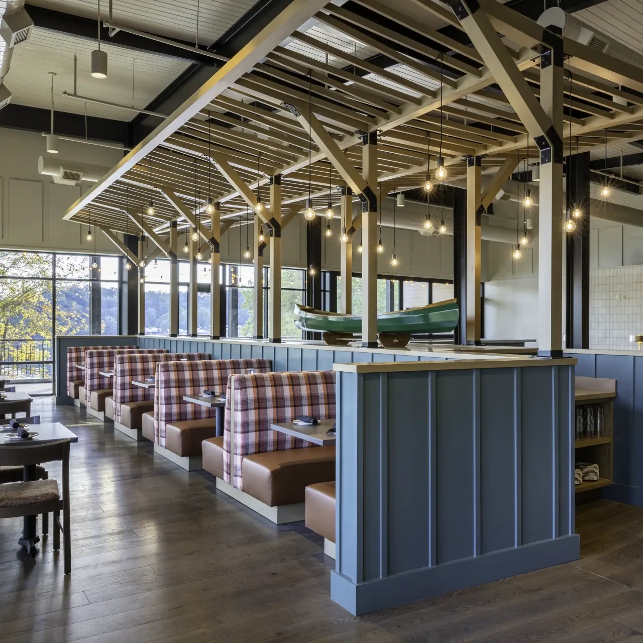 Inside a restaurant with wooden aesthetic, wooden tables and booths, and a canoe in the middle of the room raised up