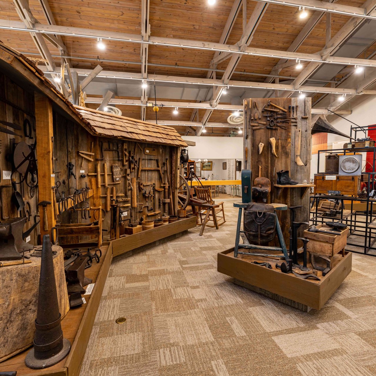 Museum interior with historical tools displayed on rustic wooden walls and modern installations. Warm lighting and vintage artifacts evoke nostalgia.
