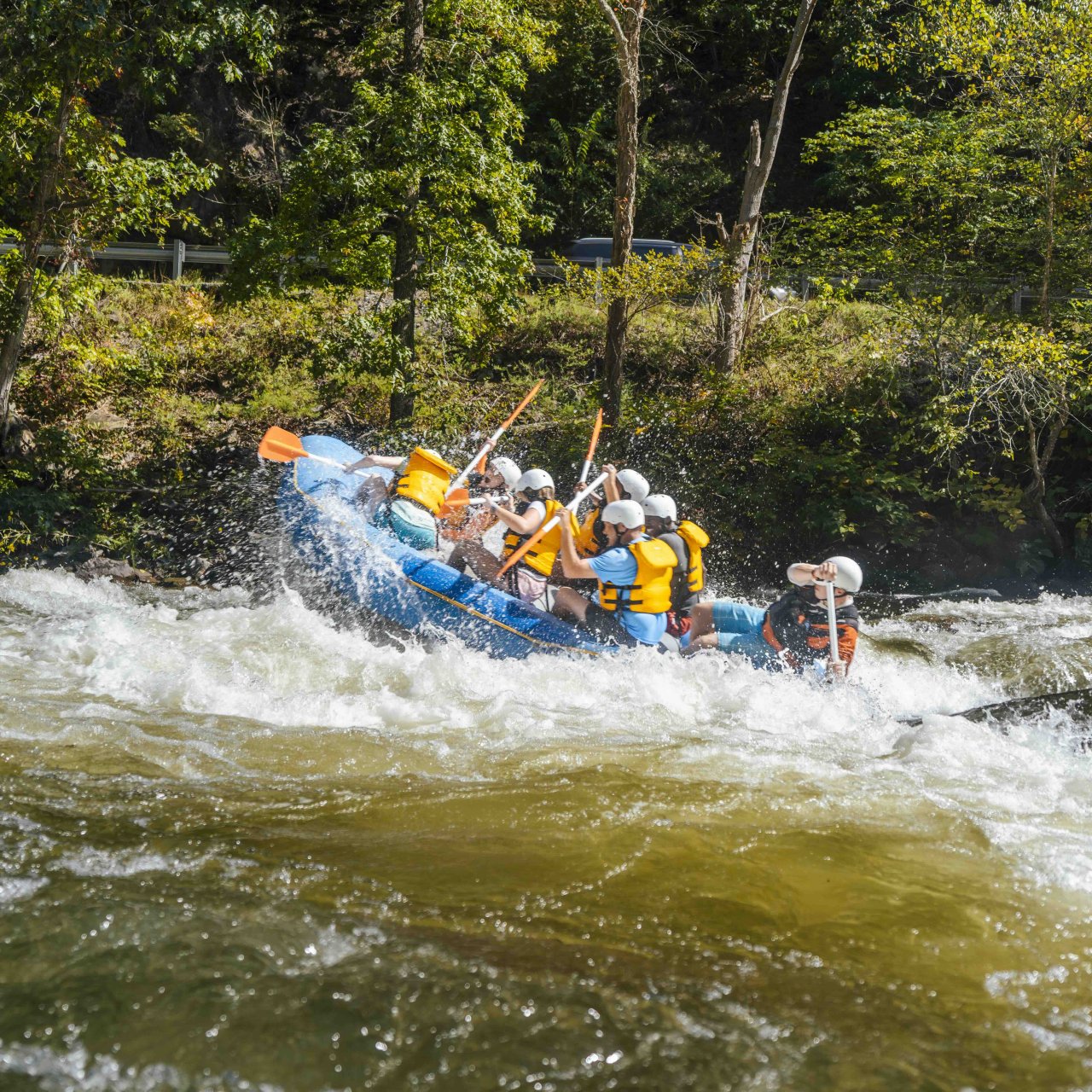 people white water rafting splashing against the rough water