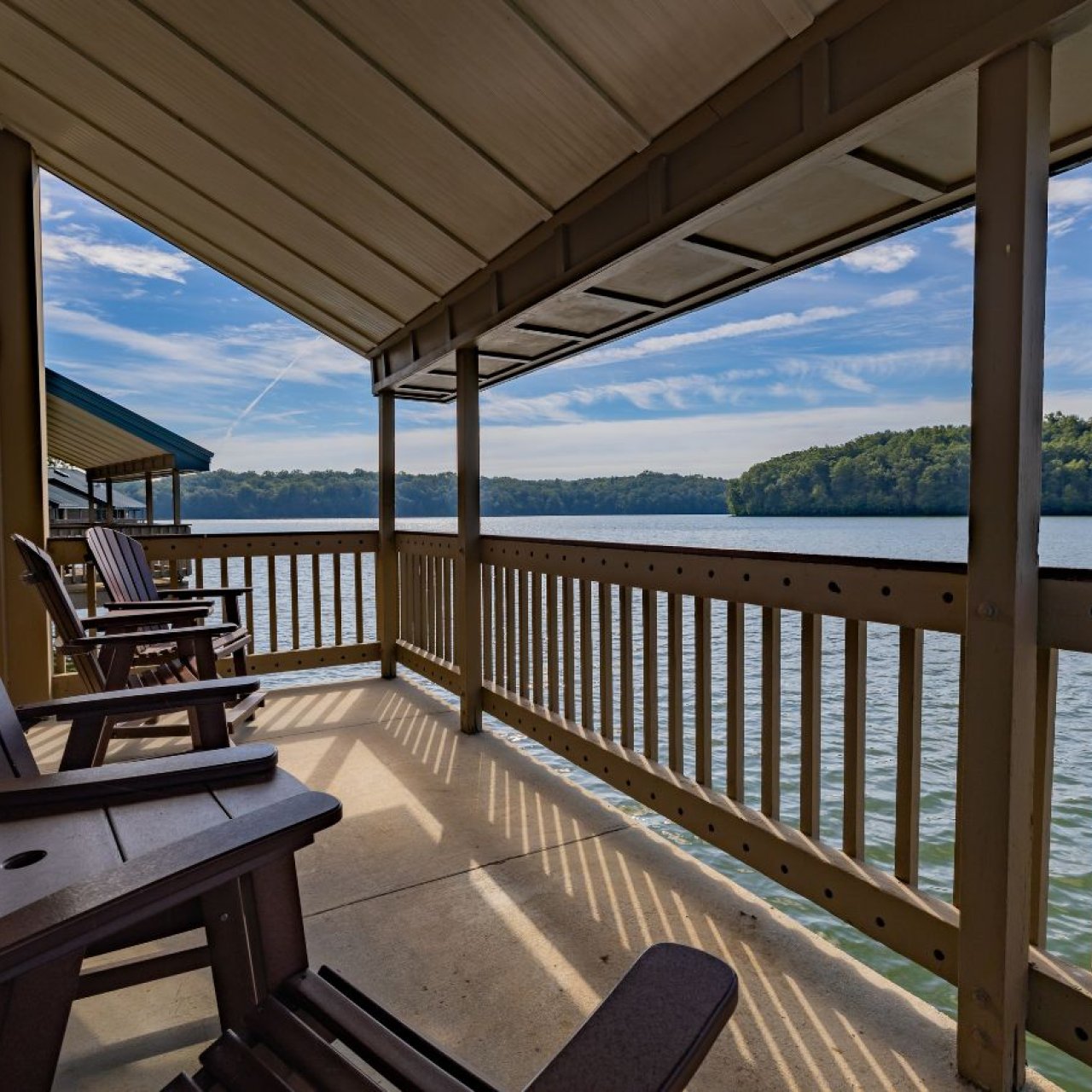 Wooden chairs on a porch overlooking a tranquil lake.