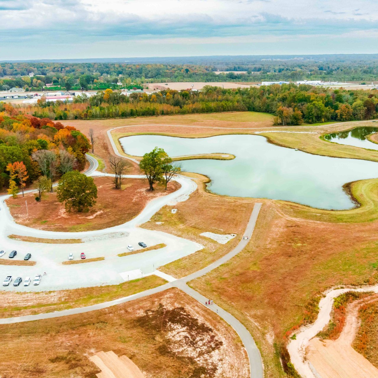 aerial view of parking lot, a pond, and some fall trees