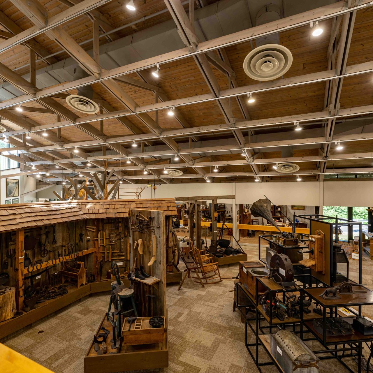 inside a museum with dated wooden artifacts and tools in the open and in display cases.
