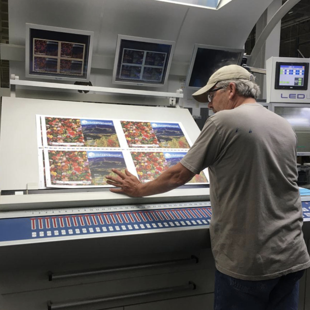 Man inspecting printed pages at a large press machine.