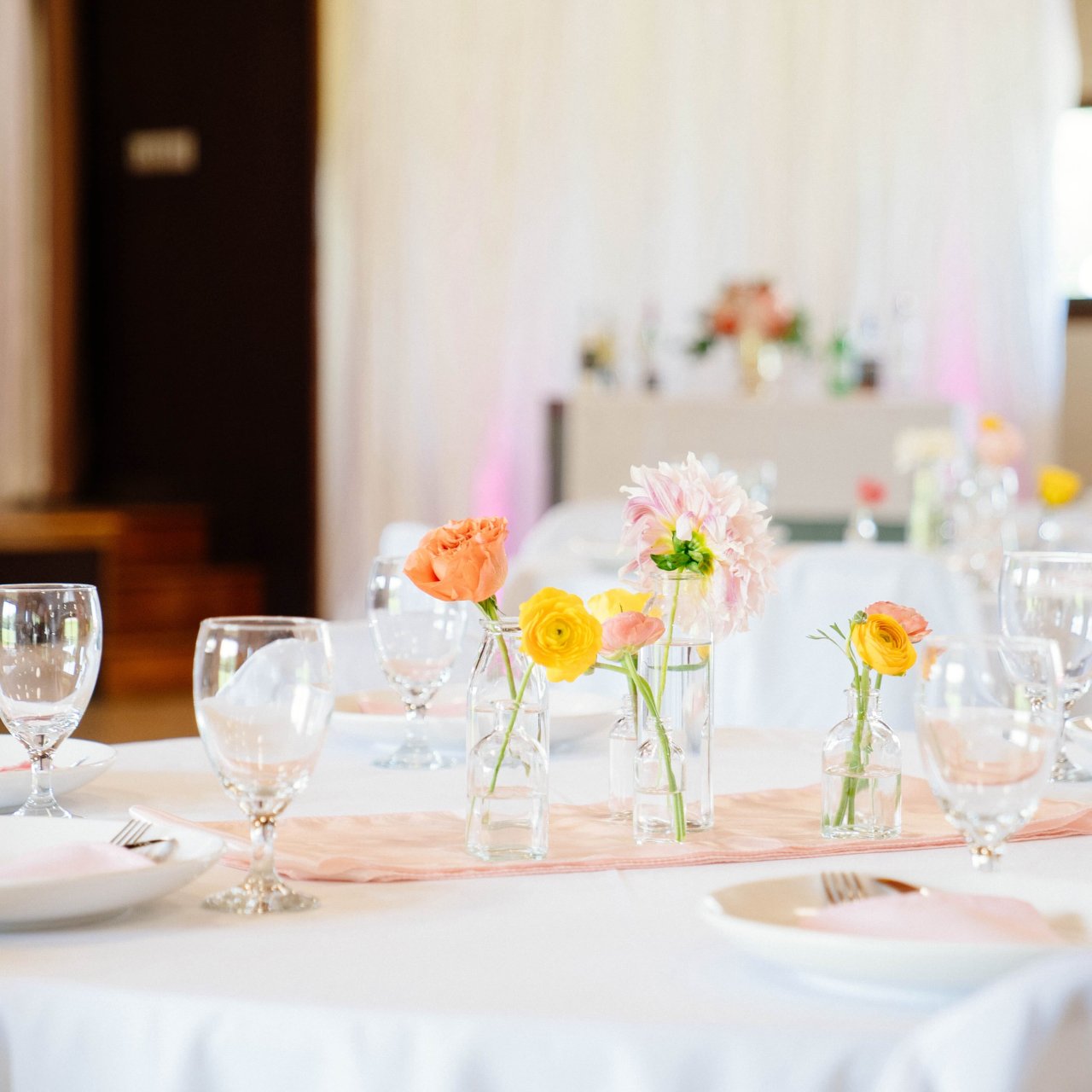 Elegantly set dining table with floral centerpieces in a bright room.