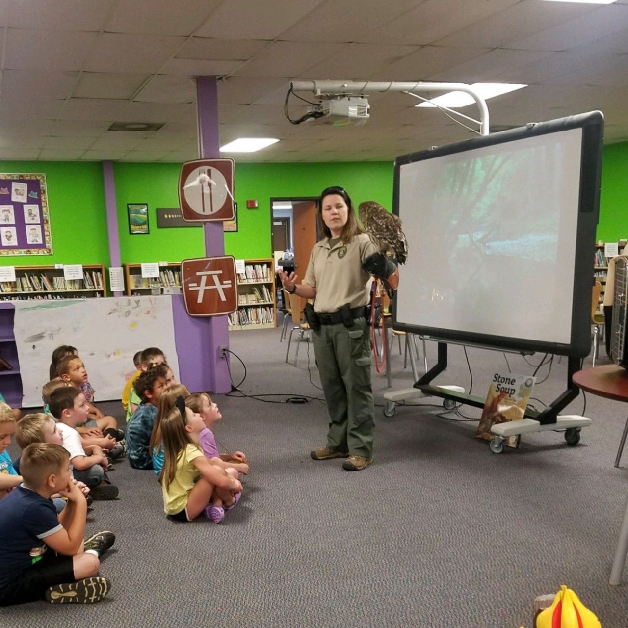 Educator with owl presenting to children in a classroom.