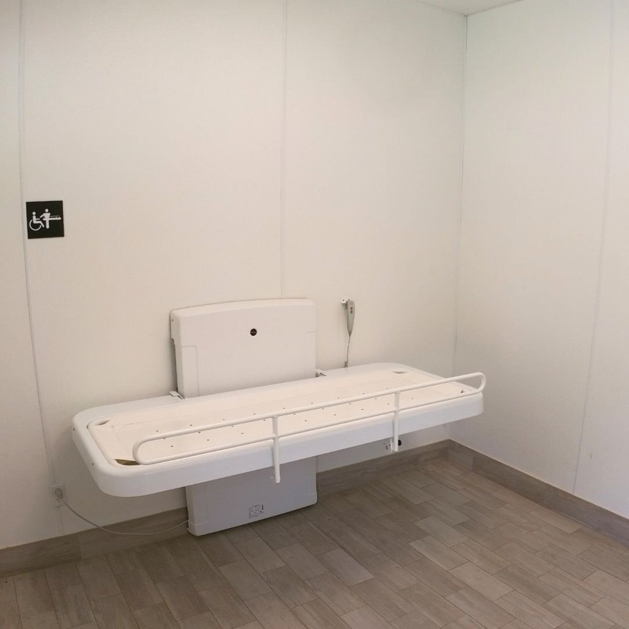 White baby changing station in a minimalist public restroom.