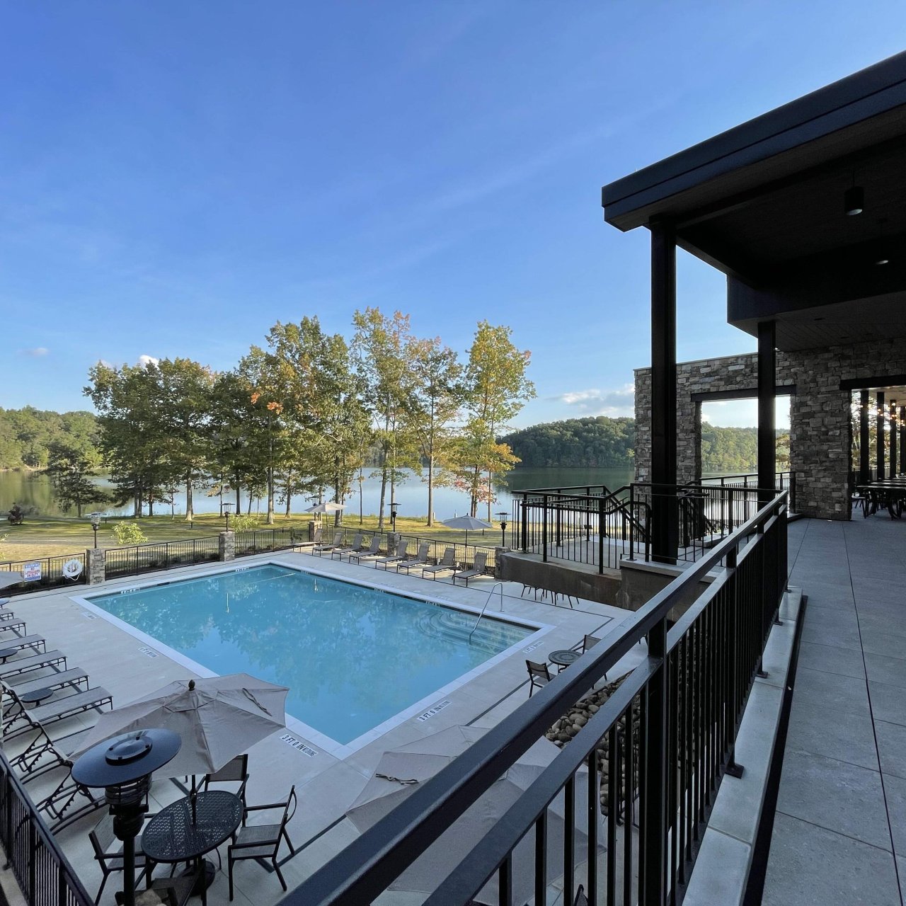Lakeside poolside terrace with dining area and scenic view.