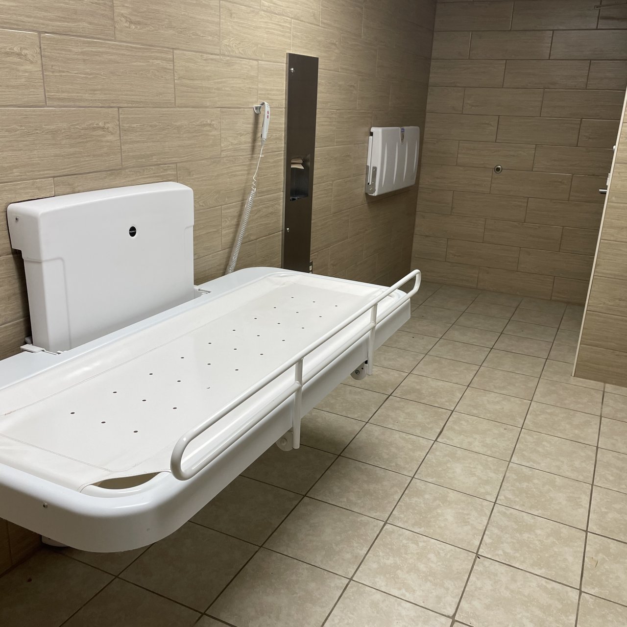 An adult-sized changing table lies open in a private restroom. 