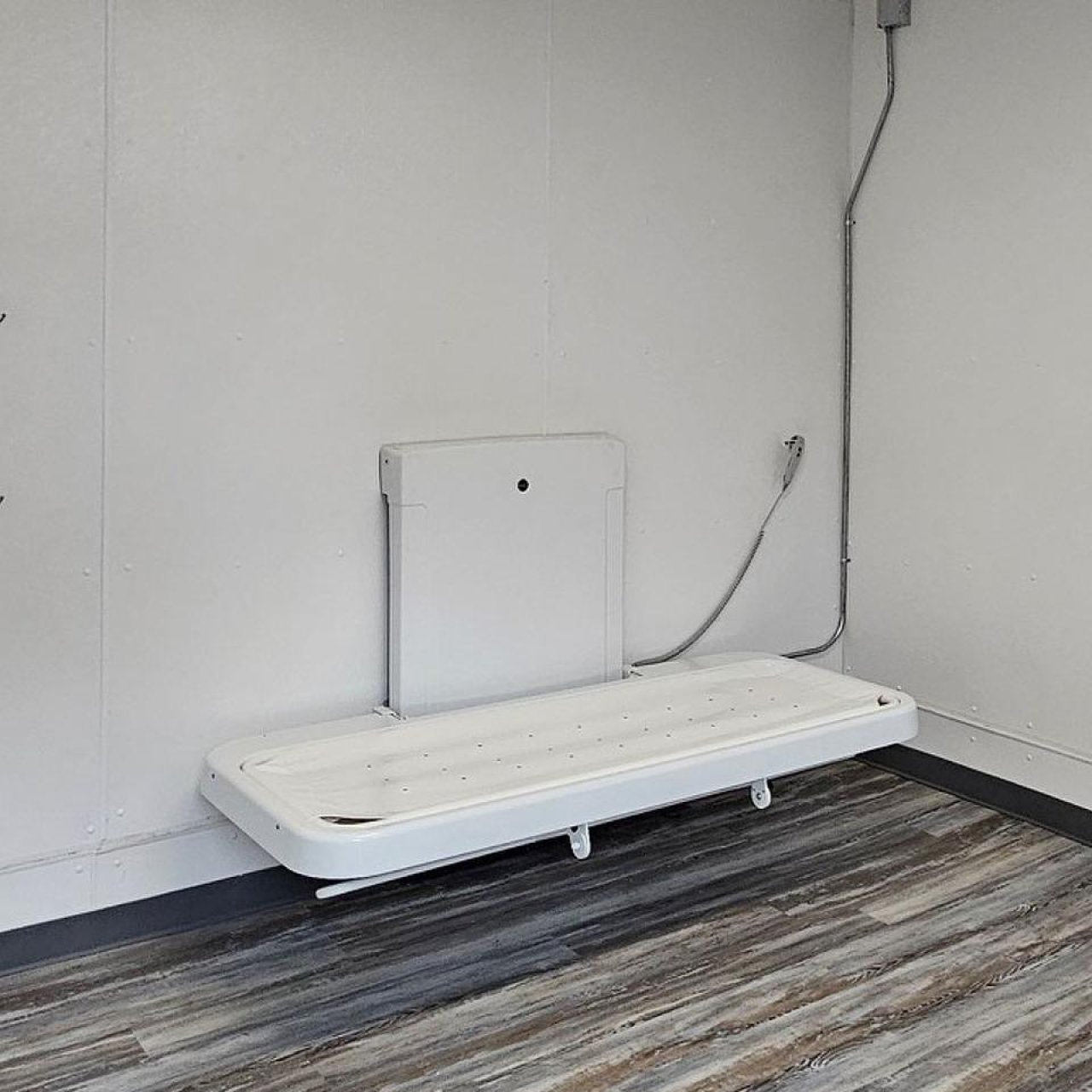 An adult-sized changing table lies open in a private restroom. 