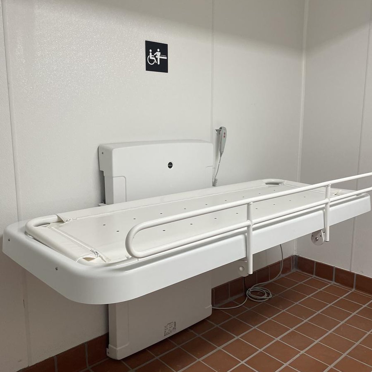 An adult-sized changing table lies open in a private restroom.