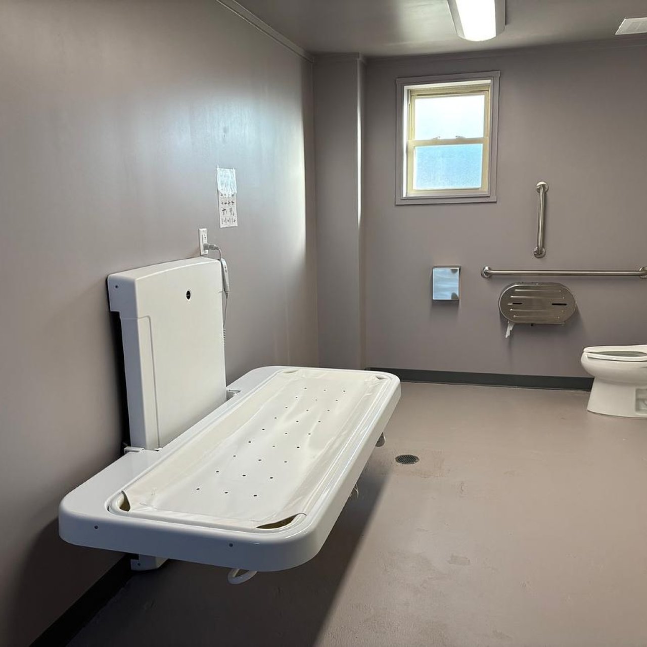 Accessible restroom with adult changing table, toilet, and sink.